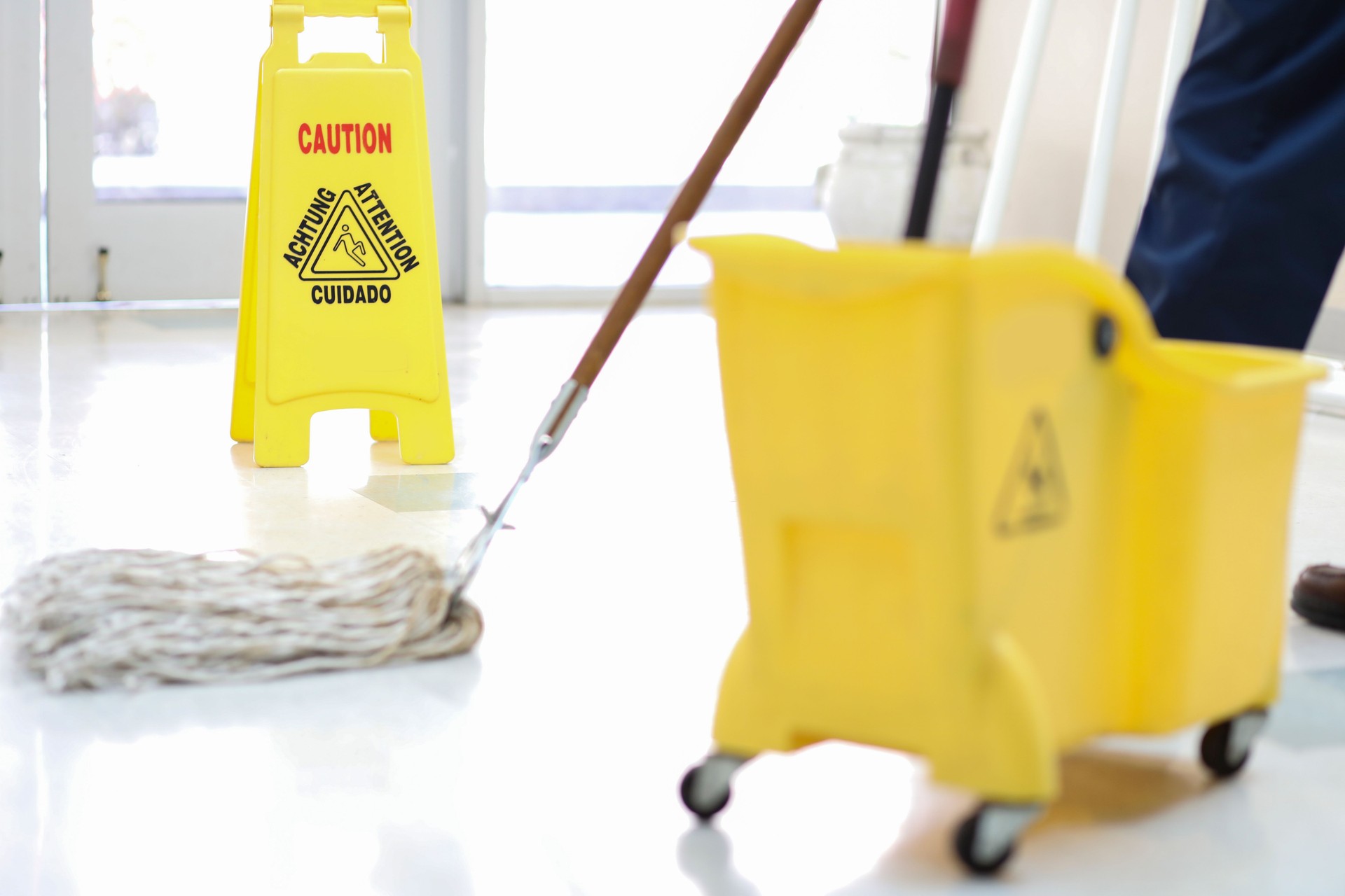 Senior Adult Janitor mops Boden bei der Einfahrt in die Büros.